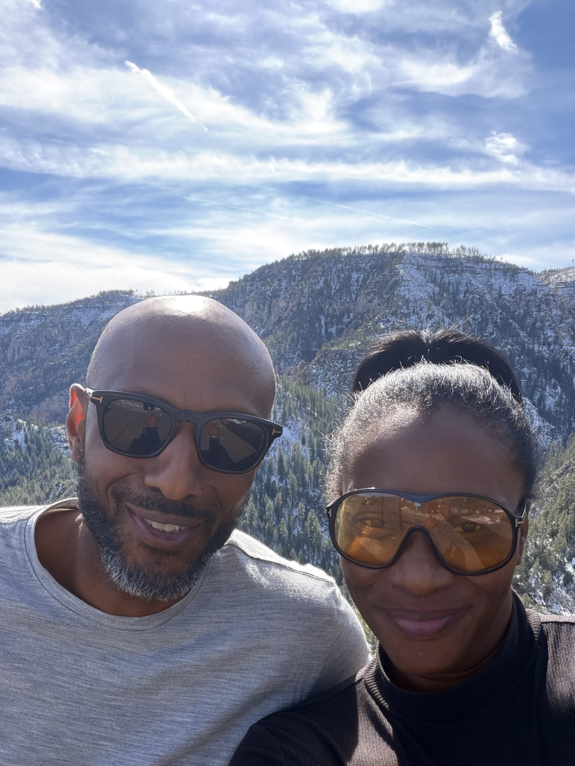 Akilah and her husband John with snow-covered mountains behind them.